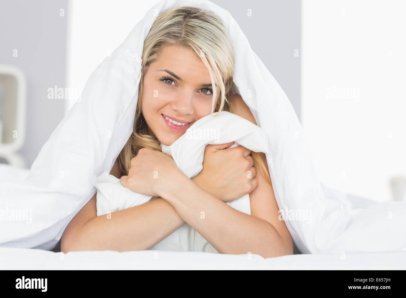 Smiling relaxed young woman hugging pillow in bed Stock Photo Alamy