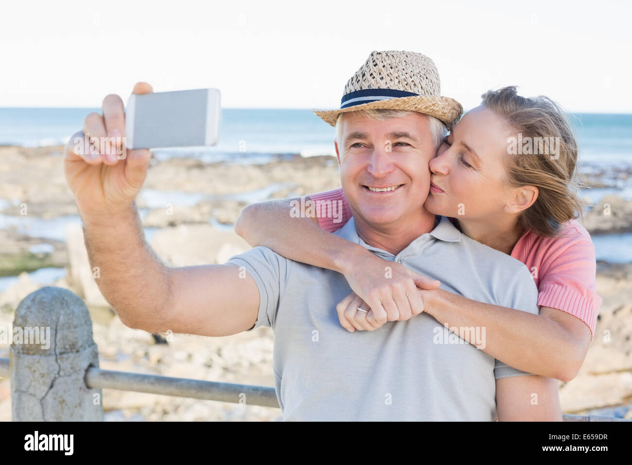 Happy casual couple taking a selfie by the coast Stock Photo