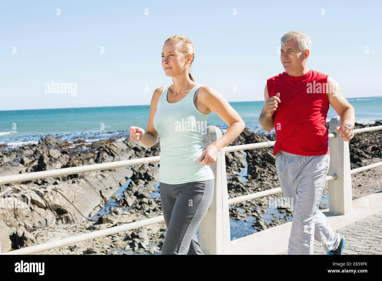 Fit mature couple jogging on the pier Stock Photo