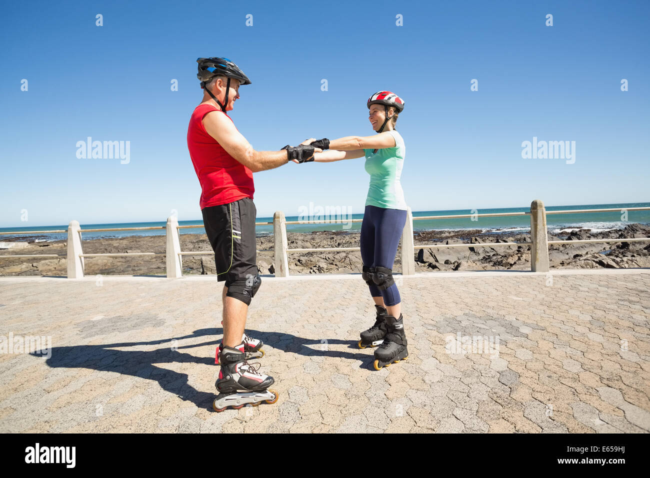 Fit mature couple rollerblading on the pier Stock Photo