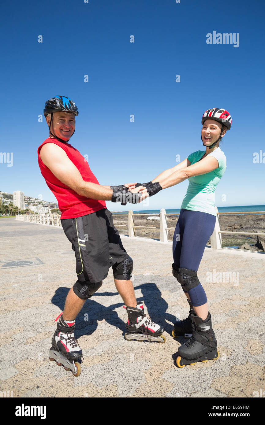 Fit mature couple rollerblading on the pier Stock Photo