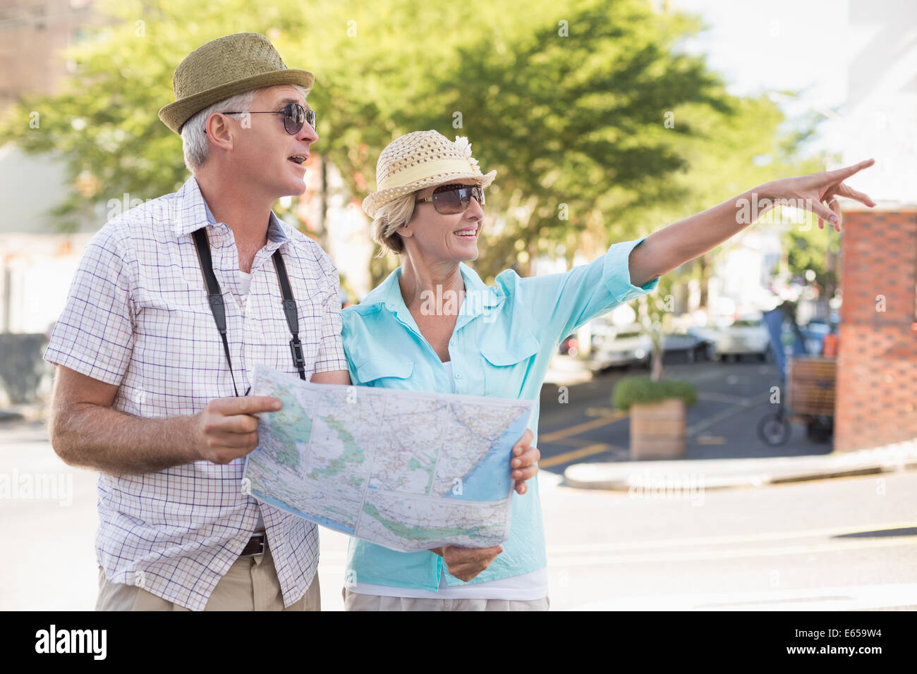 Happy tourist couple using map in the city Stock Photo