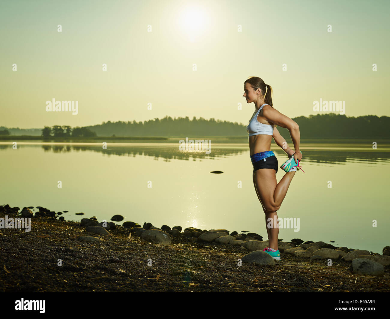 Young fitness woman stretching on the beach, sunrise on background, copy space Stock Photo