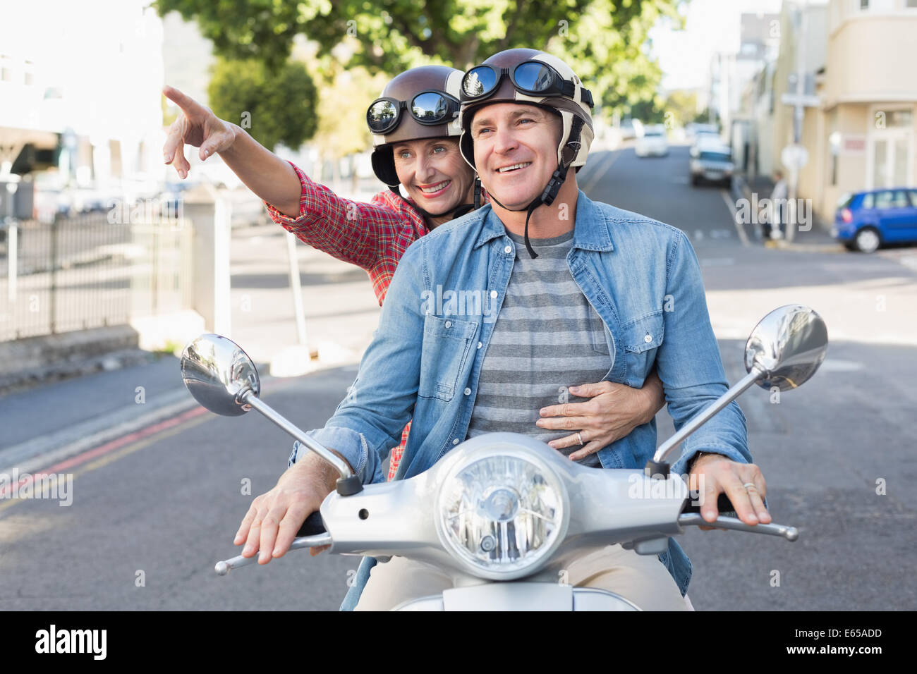 Happy mature couple riding a scooter in the city Stock Photo