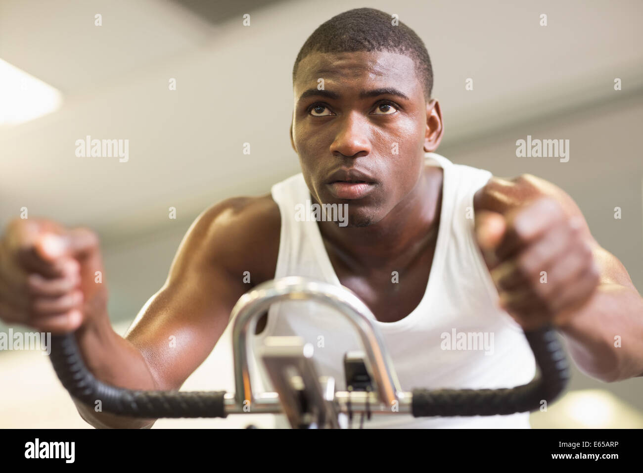 Determined man working out on exercise bike at gym Stock Photo