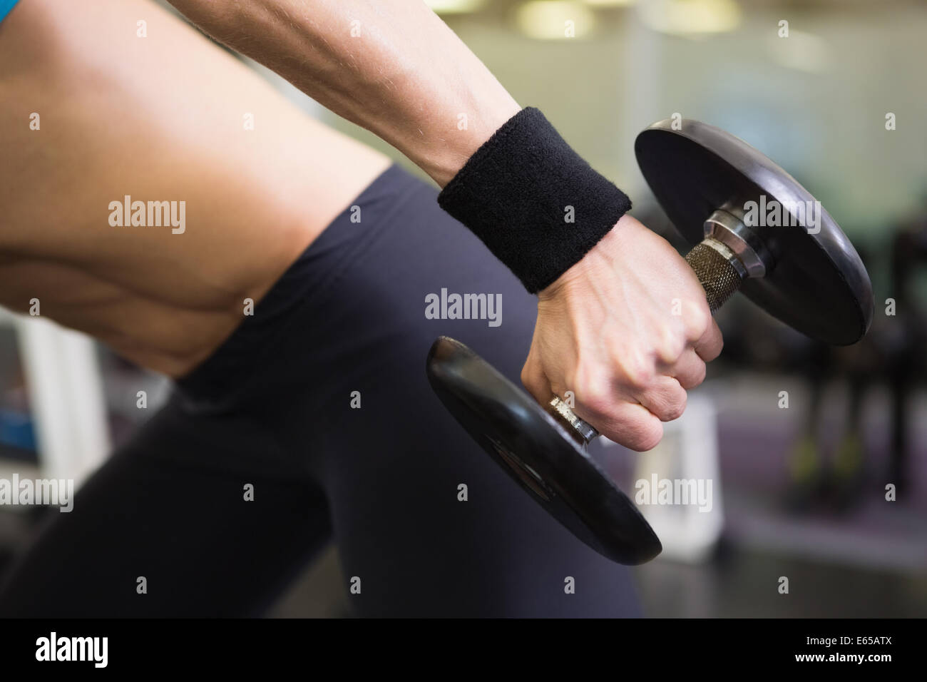 Mid section of fit woman exercising with dumbbell in gym Stock Photo