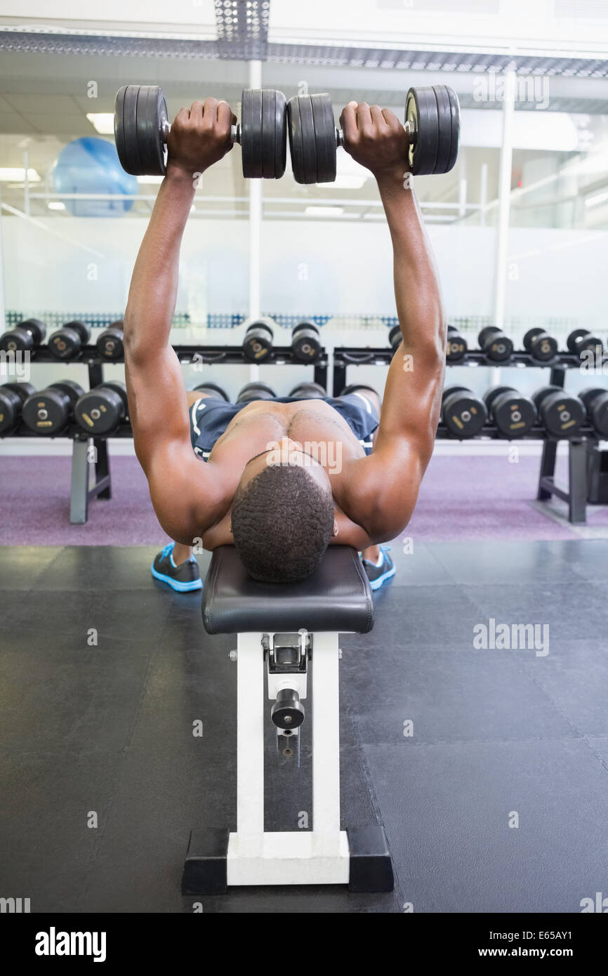 Shirtless man exercising with dumbbells in gym Stock Photo