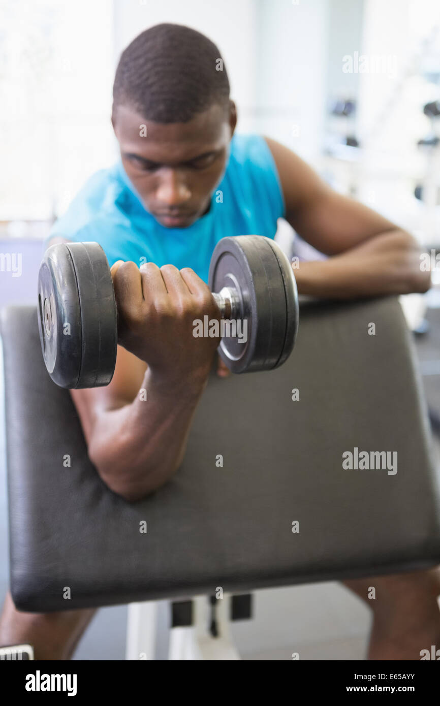 Young man exercising with dumbbell in gym Stock Photo