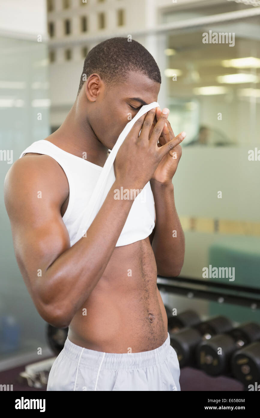 Fit man wiping sweat after workout in gym Stock Photo
