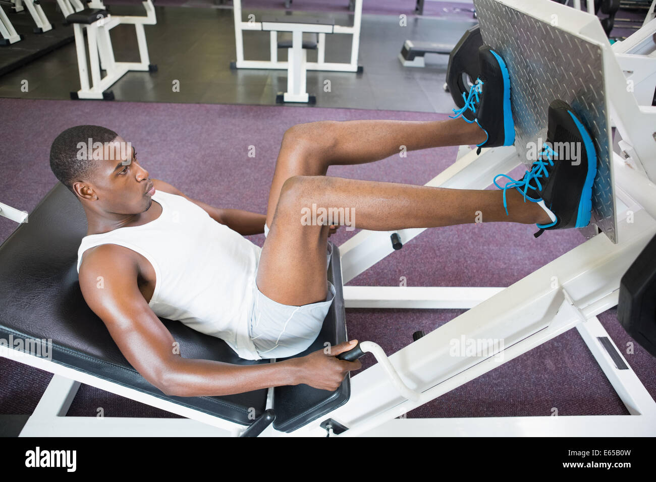 Male weightlifter doing leg presses in gym Stock Photo