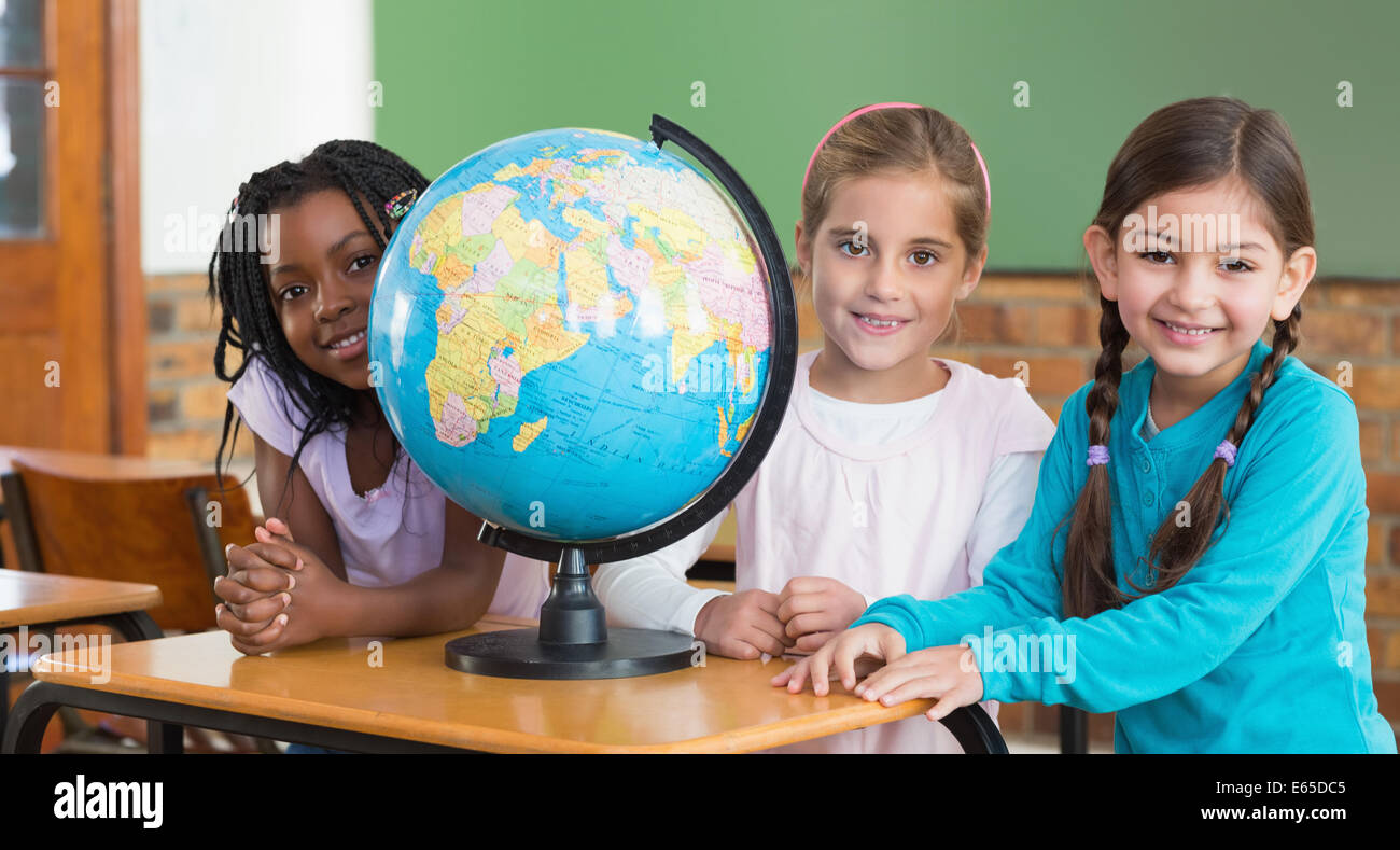 Cute pupils sitting in classroom with globe Stock Photo - Alamy