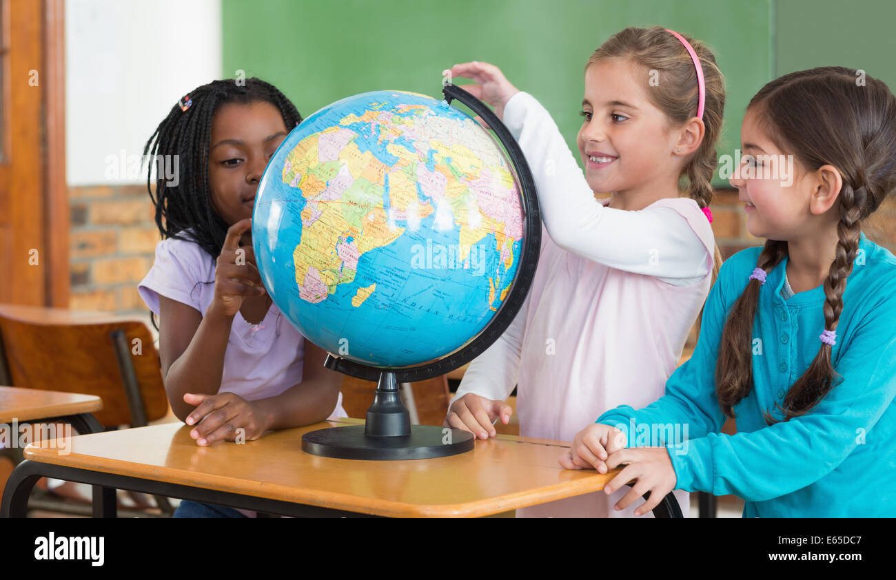 Cute pupils sitting in classroom with globe Stock Photo - Alamy