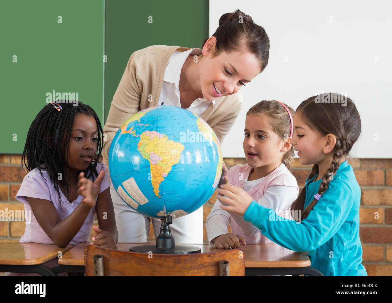 Cute pupils and teacher in classroom with globe Stock Photo - Alamy