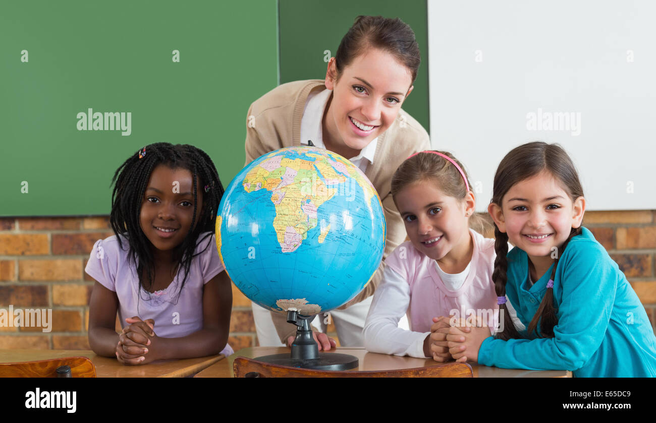 Cute pupils and teacher in classroom with globe Stock Photo - Alamy