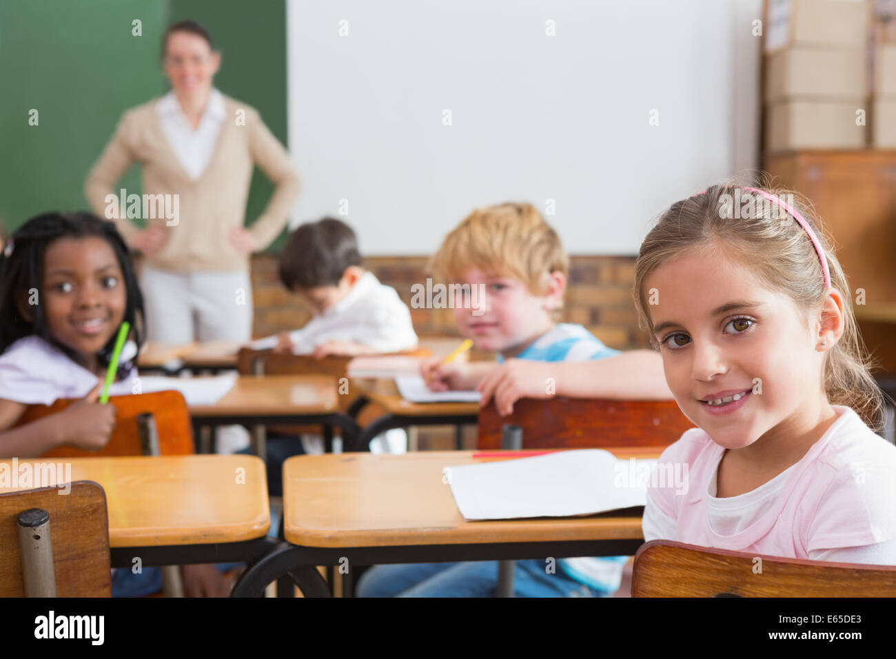 Pupils and teacher smiling at camera in classroom Stock Photo Alamy