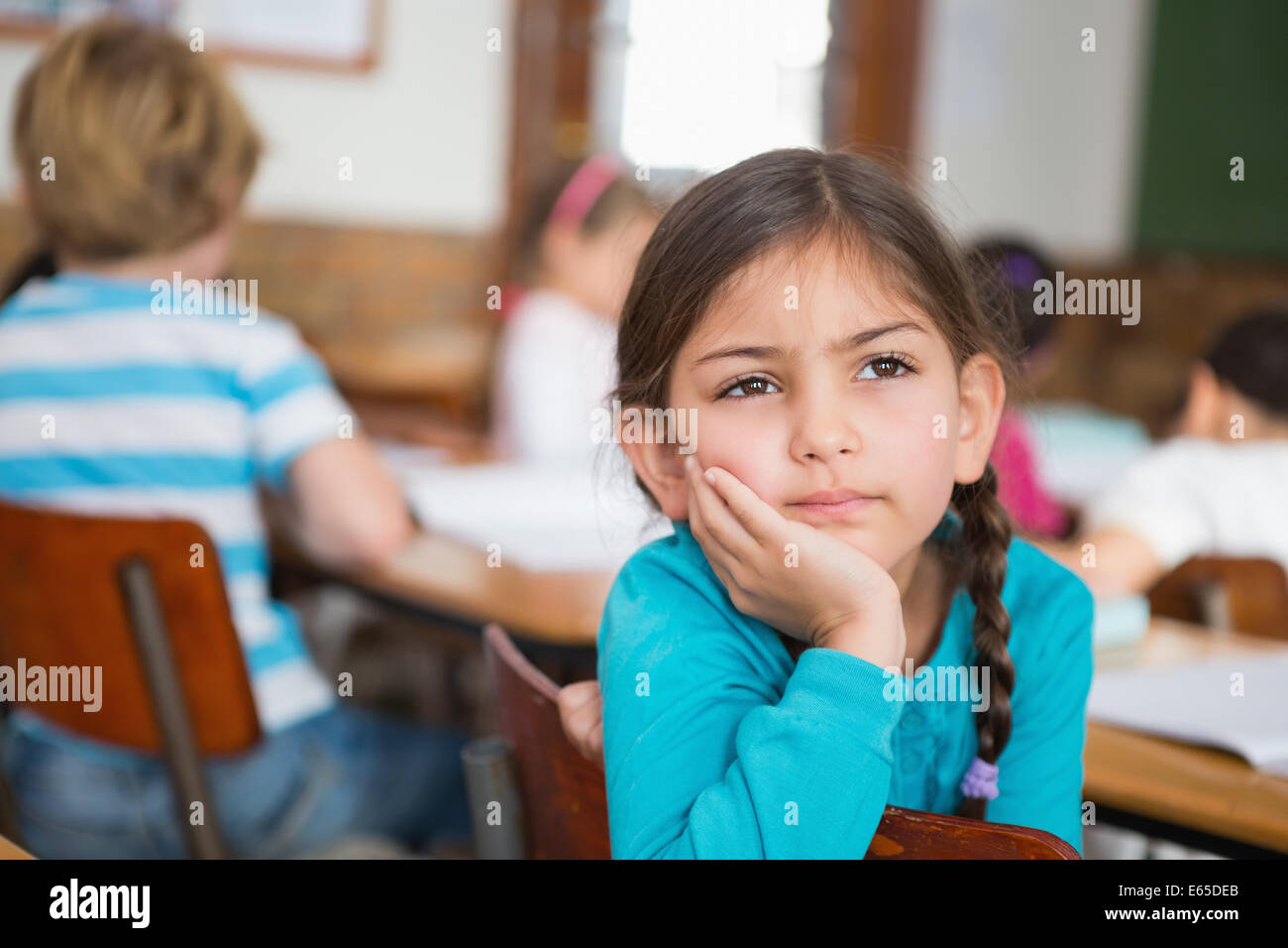 Thoughtful pupil sitting at her desk Stock Photo - Alamy
