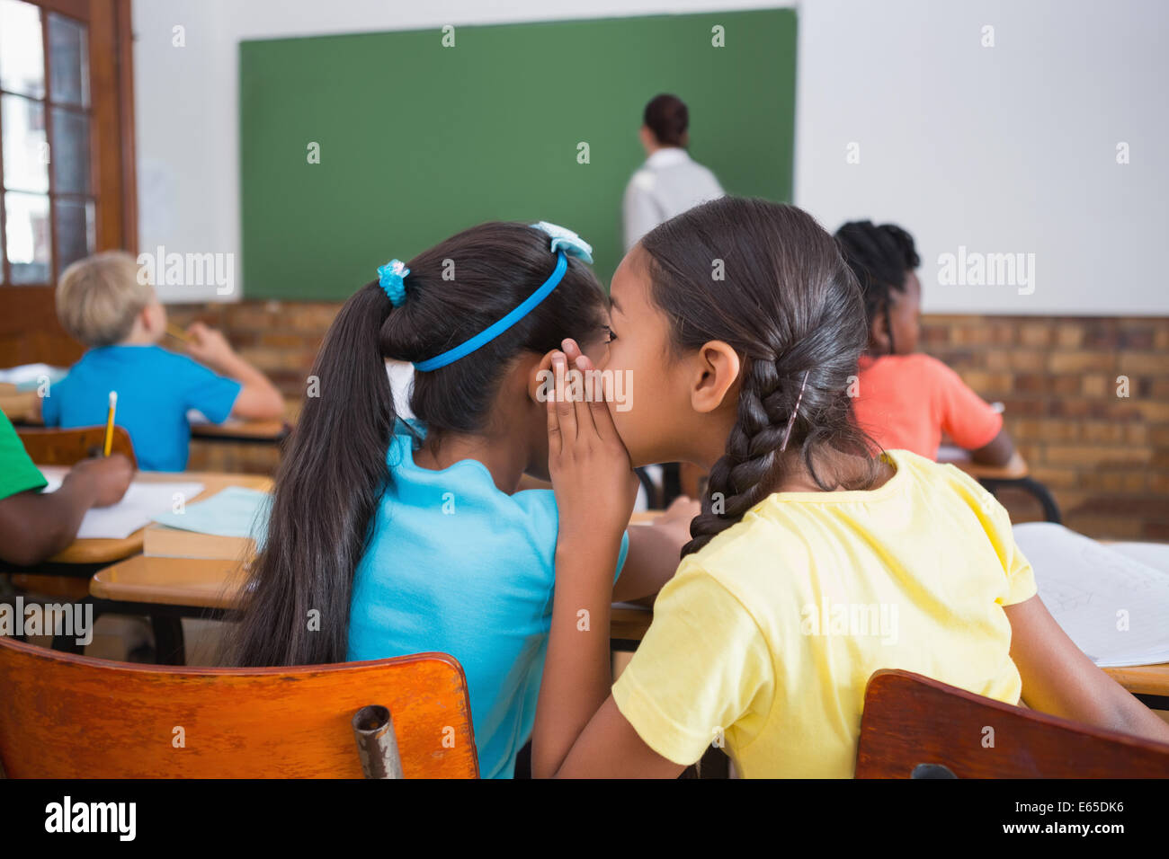 Cute pupils whispering in classroom Stock Photo - Alamy