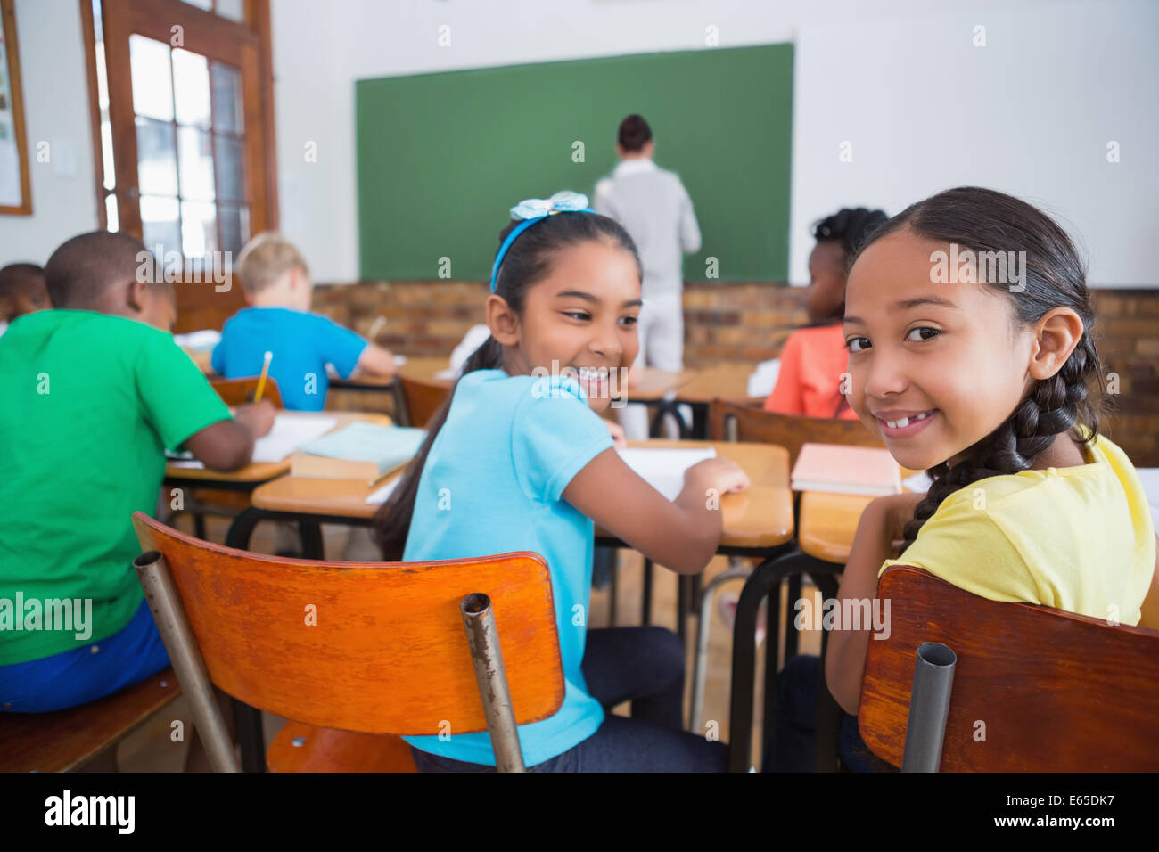 Cute pupils smiling at camera in classroom Stock Photo - Alamy