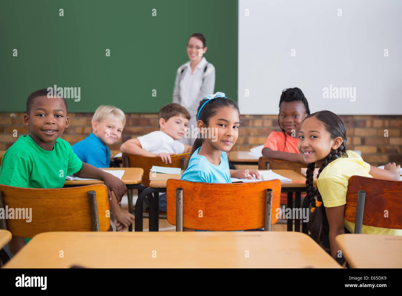 Cute pupils smiling at camera in classroom Stock Photo - Alamy