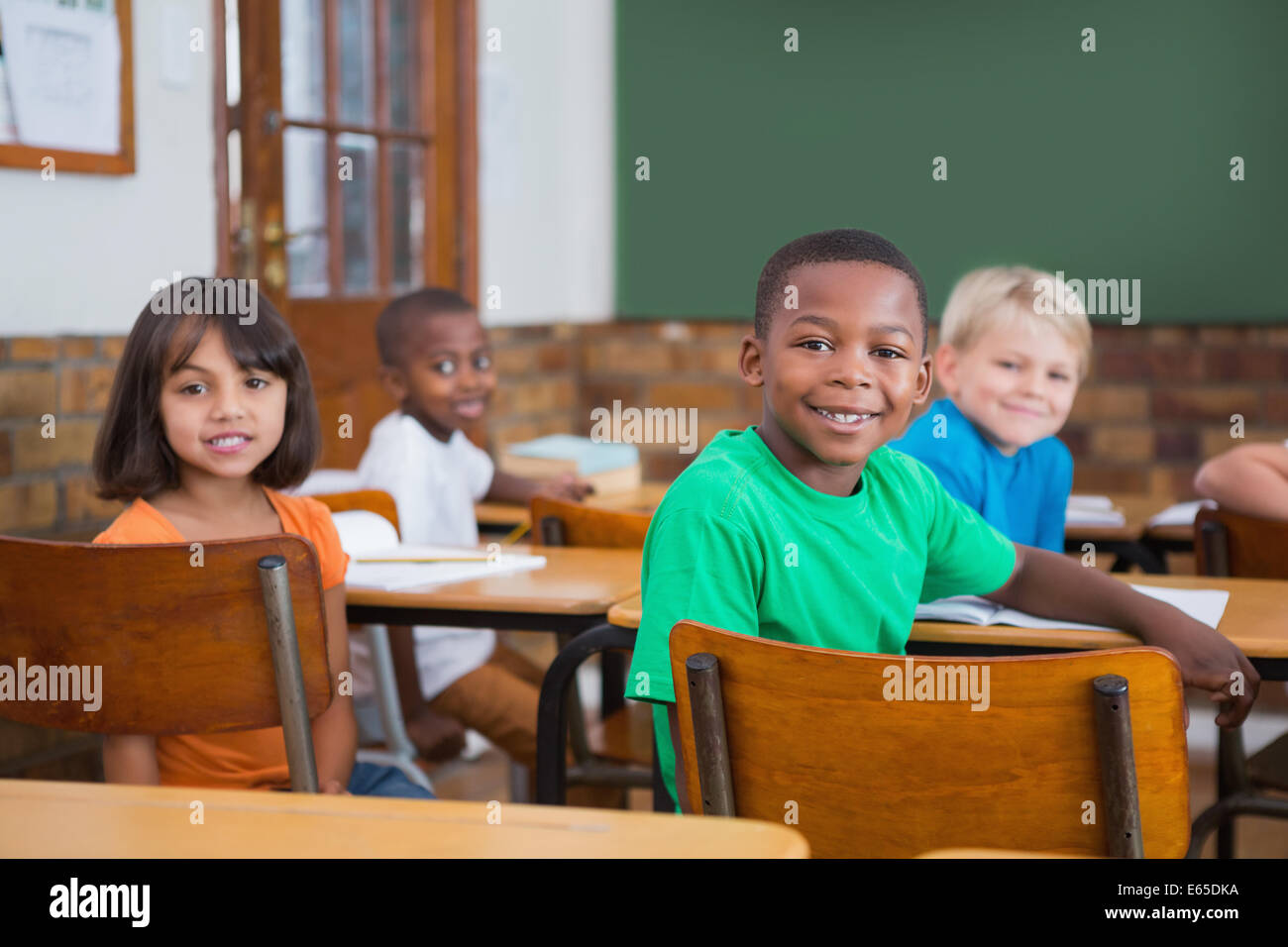 Cute pupils smiling at camera in classroom Stock Photo - Alamy
