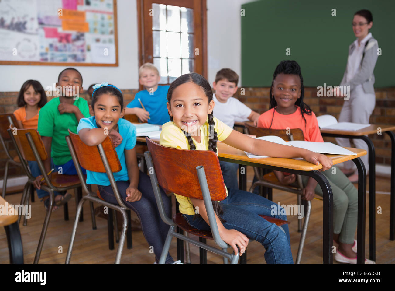Cute pupils smiling at camera in classroom Stock Photo - Alamy