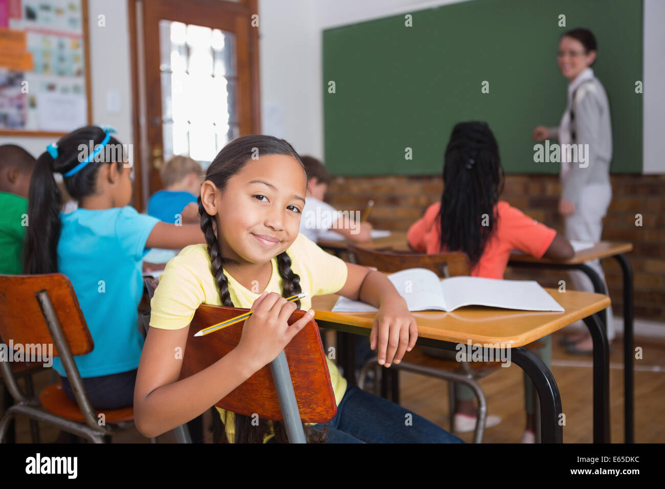 Cute pupil smiling at camera in classroom Stock Photo - Alamy