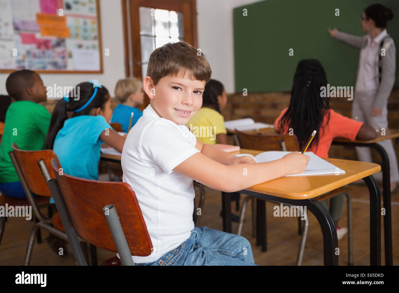 Cute pupil smiling at camera in classroom Stock Photo - Alamy