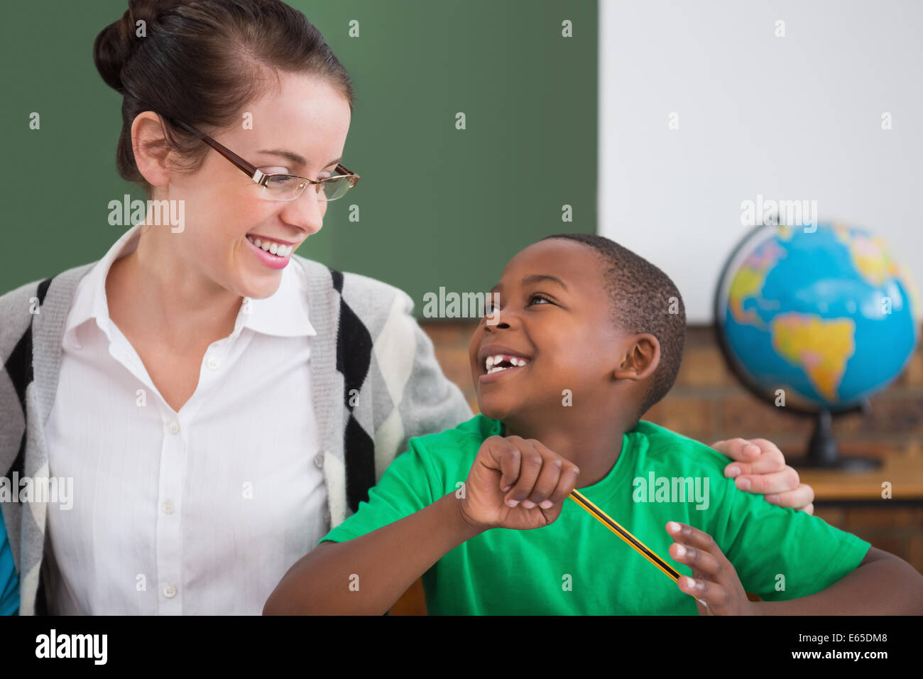 Cute pupil and teacher smiling at each other in classroom Stock Photo ...