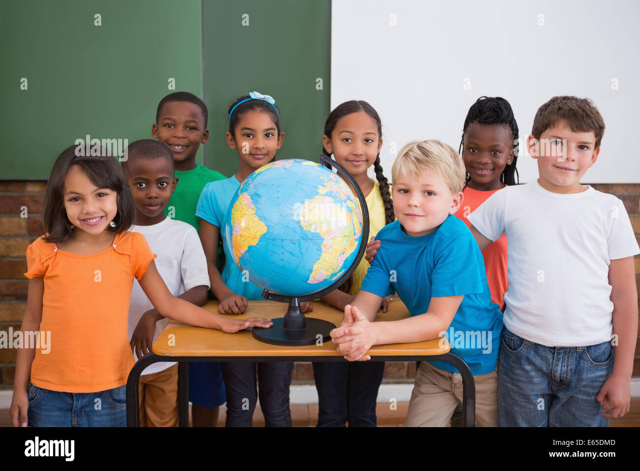 Cute pupils smiling at camera in classroom with globe Stock Photo - Alamy