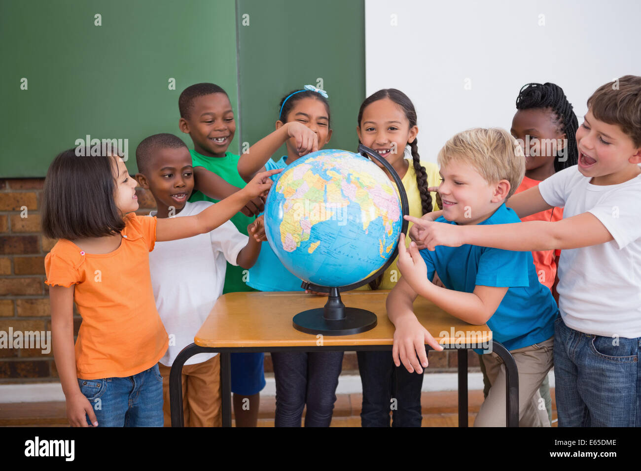 Cute pupils pointing to globe in classroom Stock Photo - Alamy