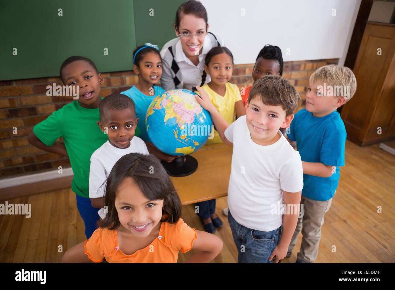 Cute pupils pointing to globe in classroom Stock Photo - Alamy