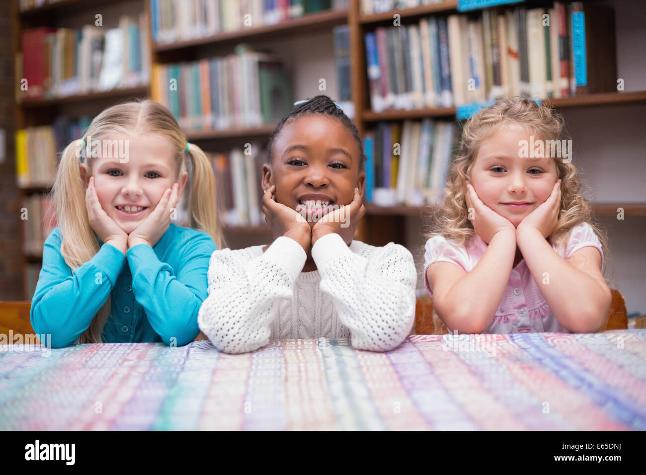 Cute pupils smiling at camera in library Stock Photo - Alamy