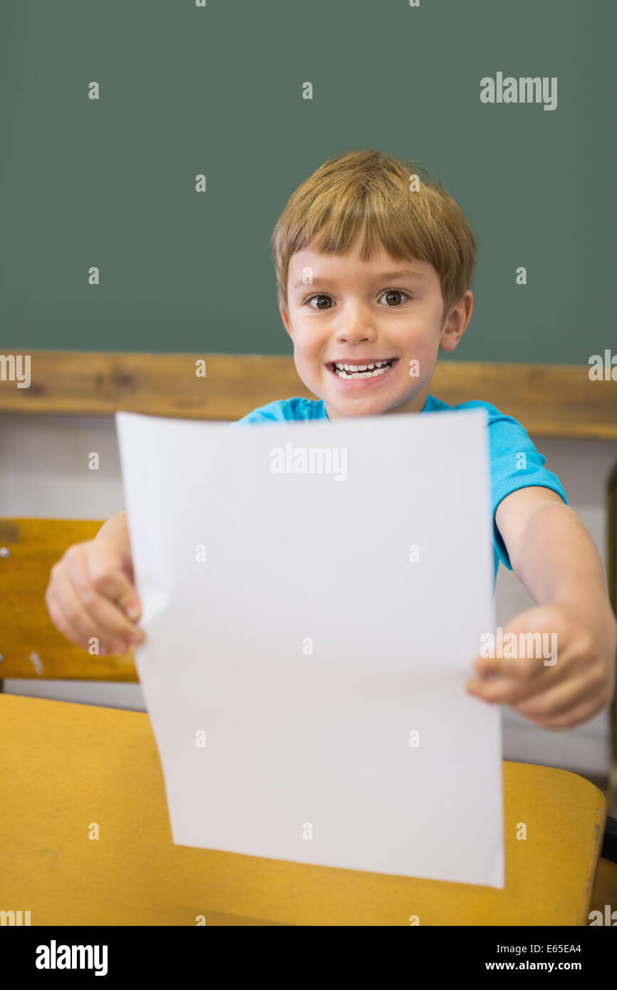 Cute pupil smiling at camera in classroom showing page Stock Photo - Alamy