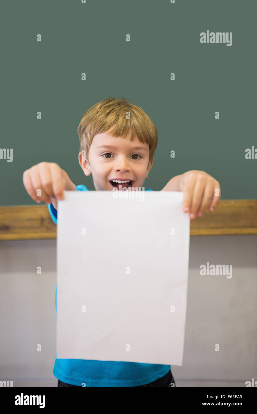 Cute pupil smiling at camera in classroom showing page Stock Photo - Alamy