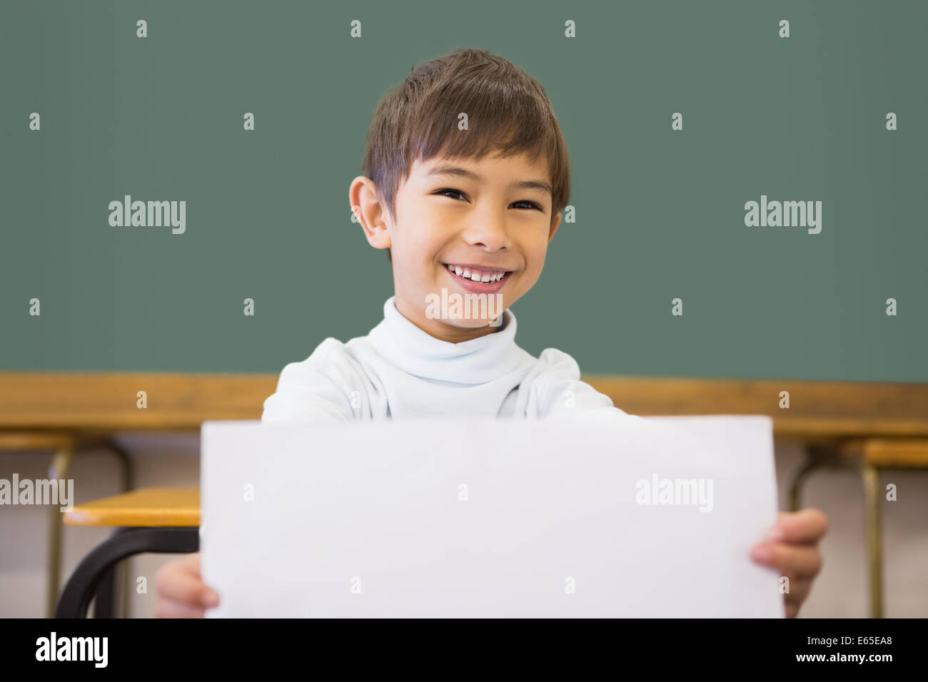 Cute pupil smiling at camera in classroom showing page Stock Photo - Alamy