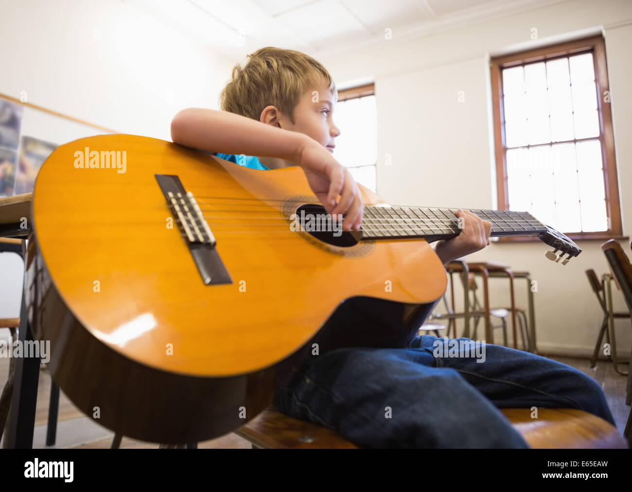 Cute pupil playing guitar in classroom Stock Photo Alamy
