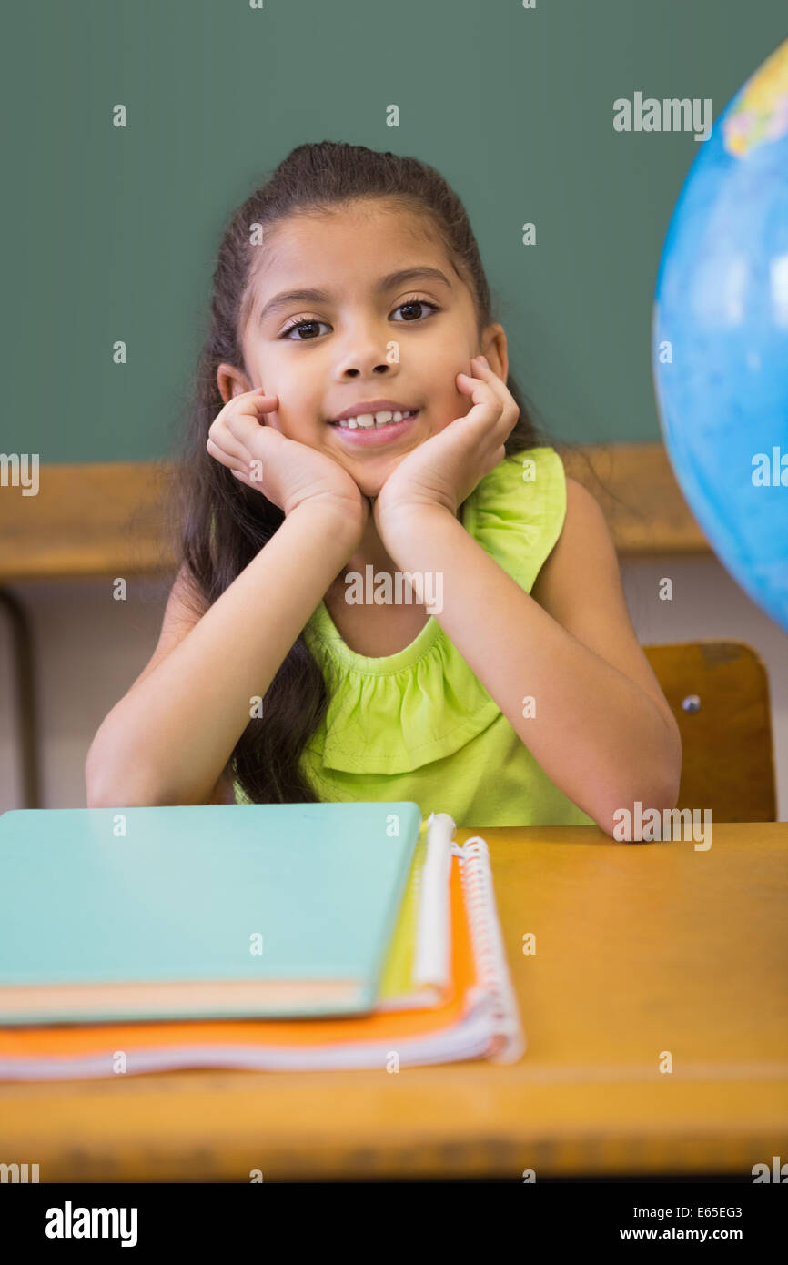 Cute pupil smiling at camera classroom with globe Stock Photo - Alamy
