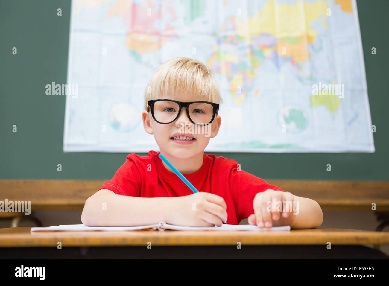 Cute pupil smiling at camera in classroom at his desk Stock Photo - Alamy