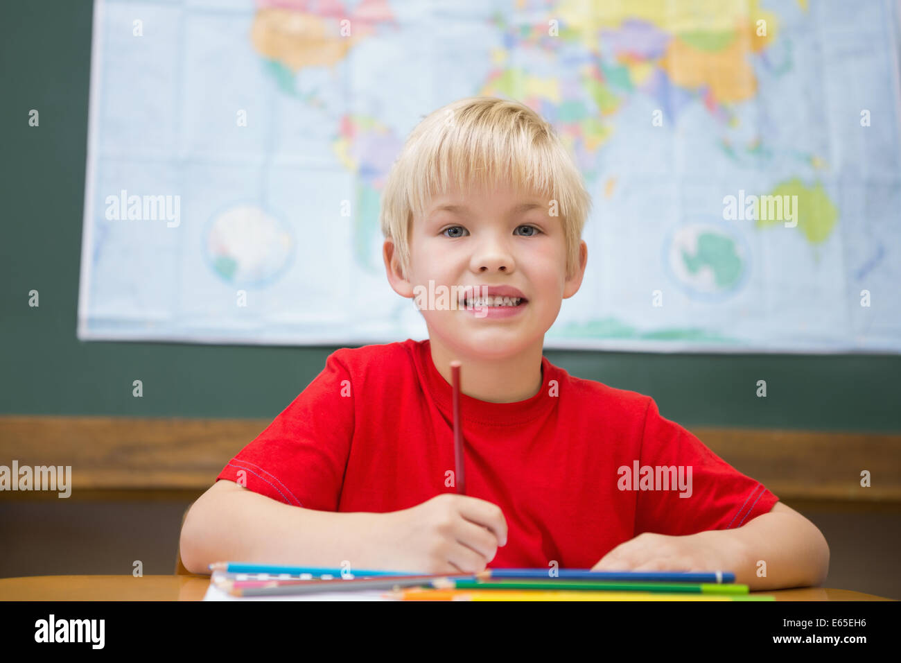 Cute pupil smiling at camera in classroom at his desk Stock Photo - Alamy