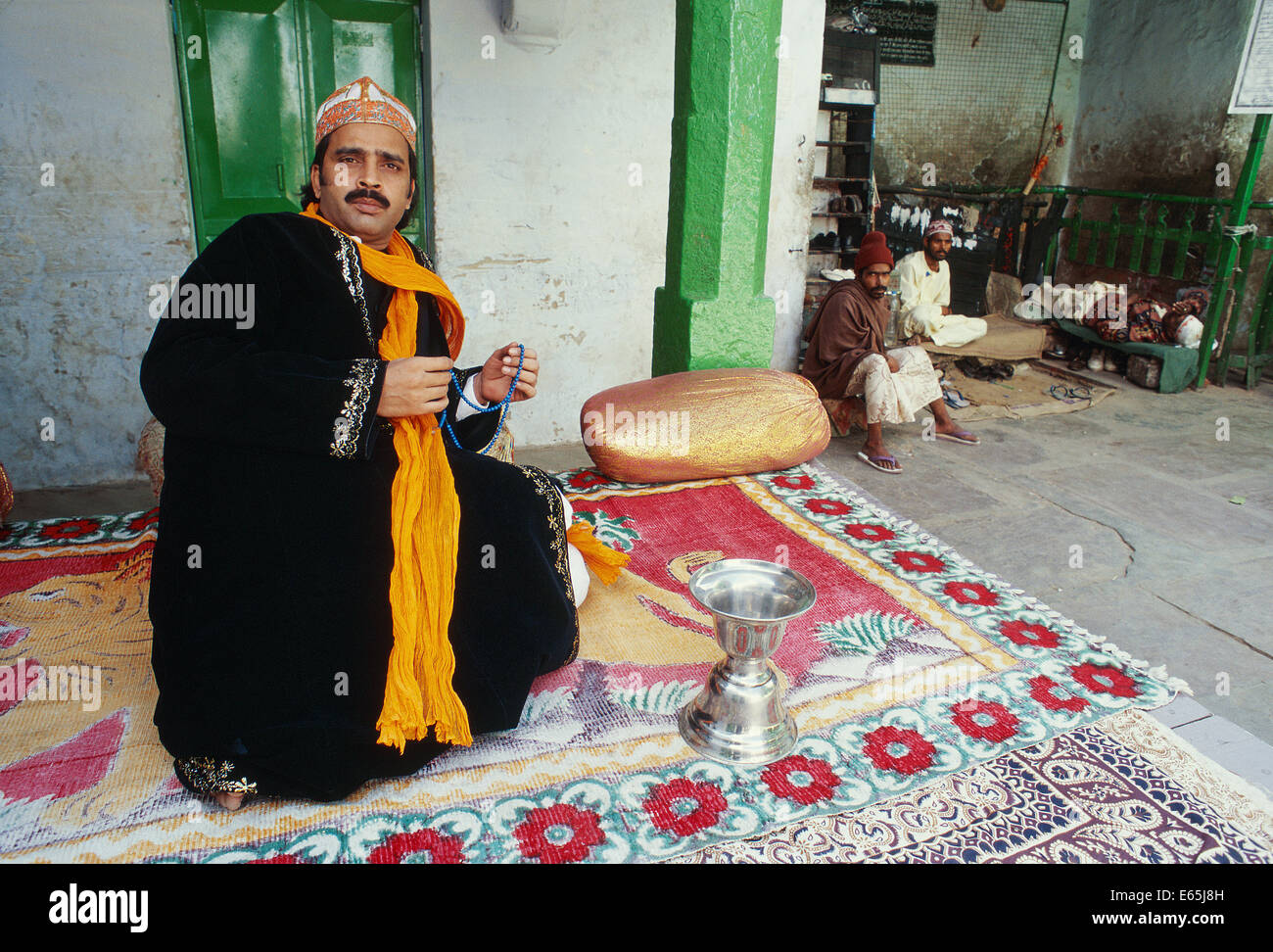 'Khadim' ( i.e. the descendant of a disciple of the sufi saint Moinuddin Chishti). In the background, shoe keepers ( India) Stock Photo