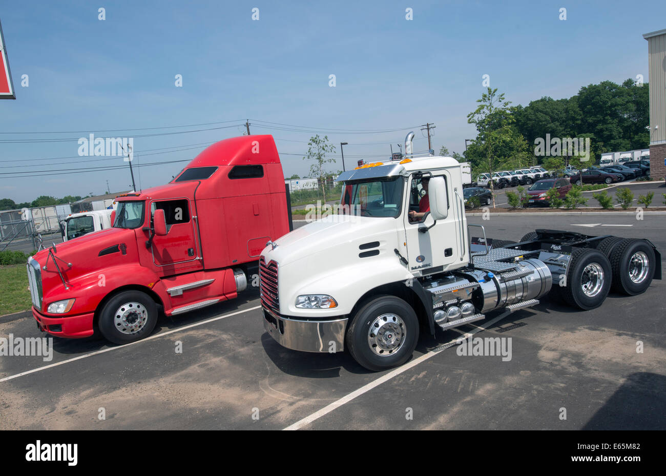 Tractor trailer truck cabs for sale.  Red one, with sleeper attached, is a Kenworth, white one a Mack. Stock Photo