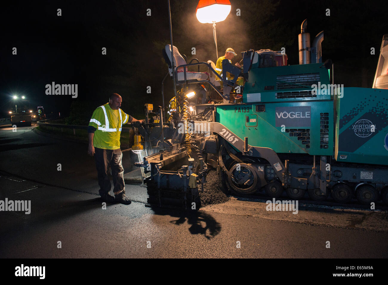 Waters Construction works on nighttime paving on the Merritt Parkway in Connecticut with tracked paving machine made by Vogele. Stock Photo