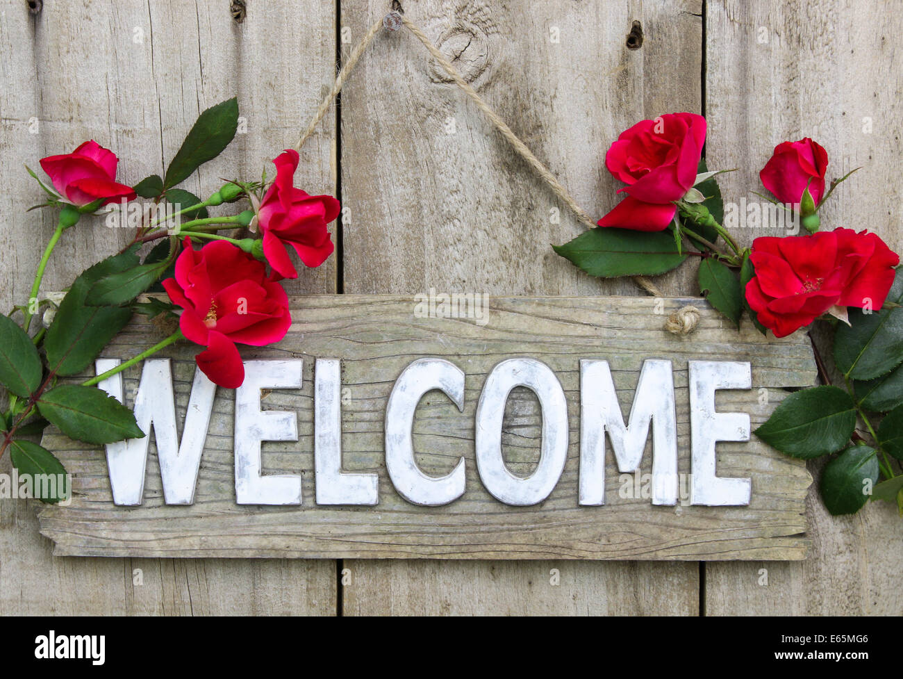 weathered-wood-welcome-sign-hanging-on-wooden-door-with-flower-border