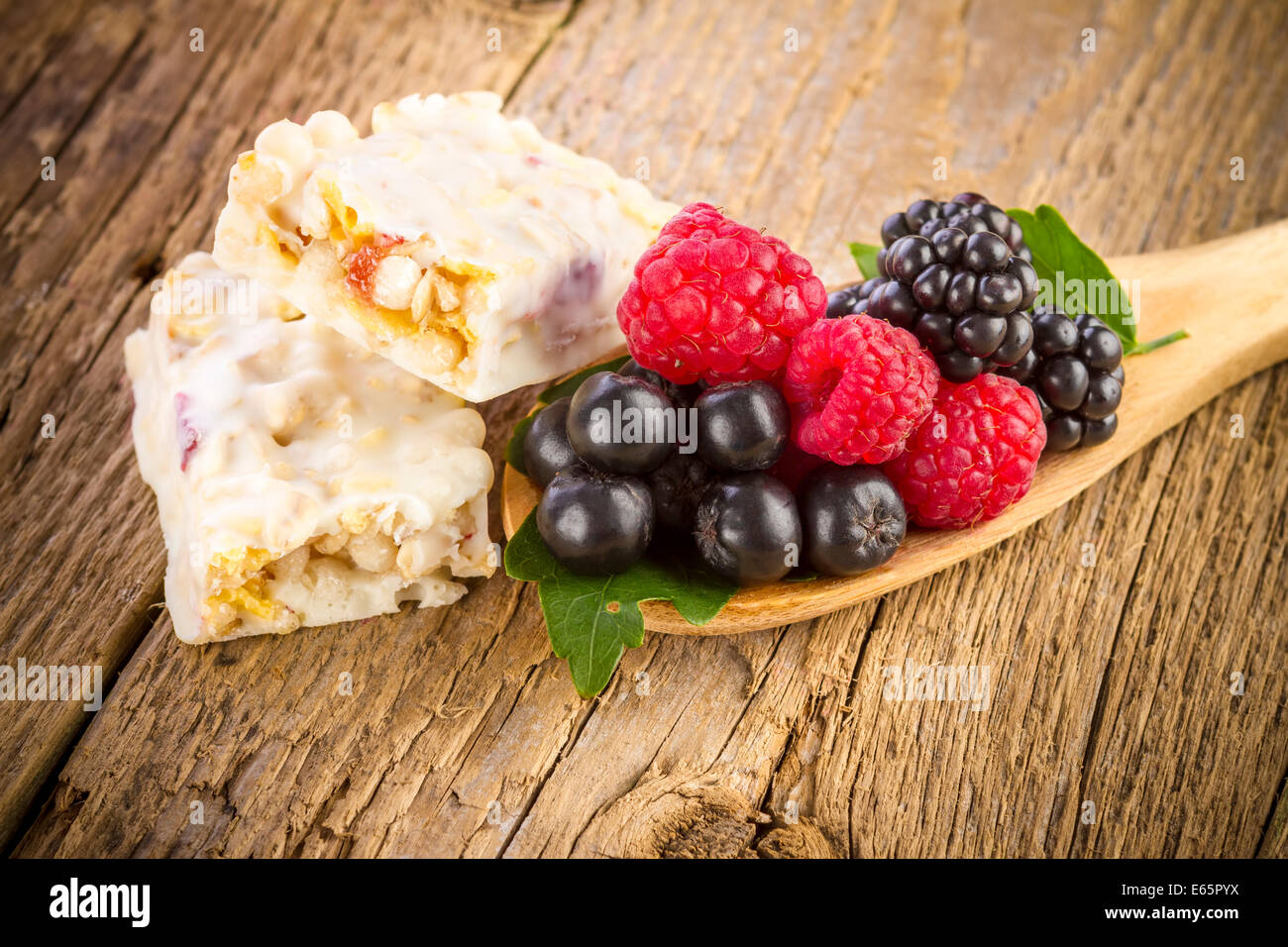 Muesli bars with fresh berries on wooden background Stock Photo