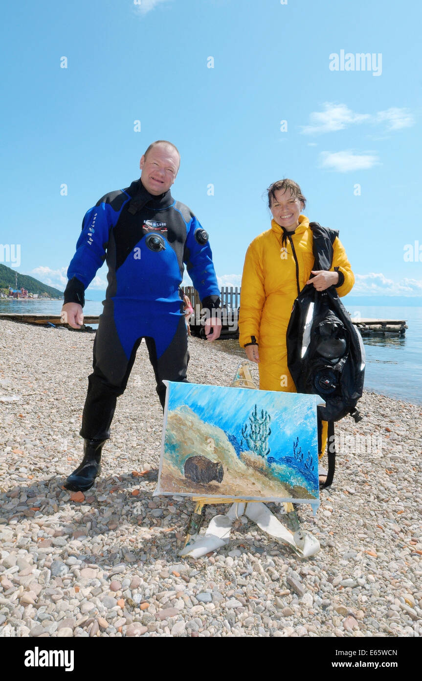 Underwater artist Yuriy Alexeev (Yuri Alekseev) and his assistant standing next to the picture painted in the water. Stock Photo