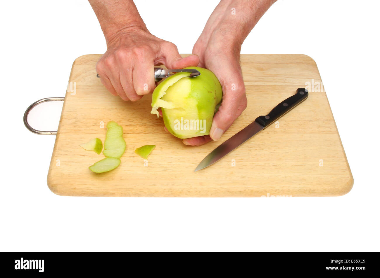 Hands peeling a cooking apple on a wooden board against a white background Stock Photo