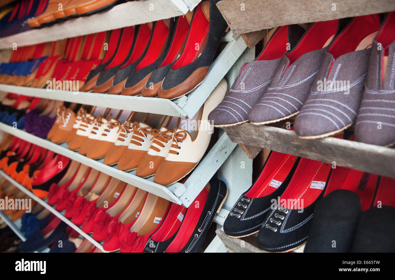 Collection of beautifully fashionable handmade shoes lined in rows on display in a store. Indonesian craftsmanship at a market stall Stock Photo