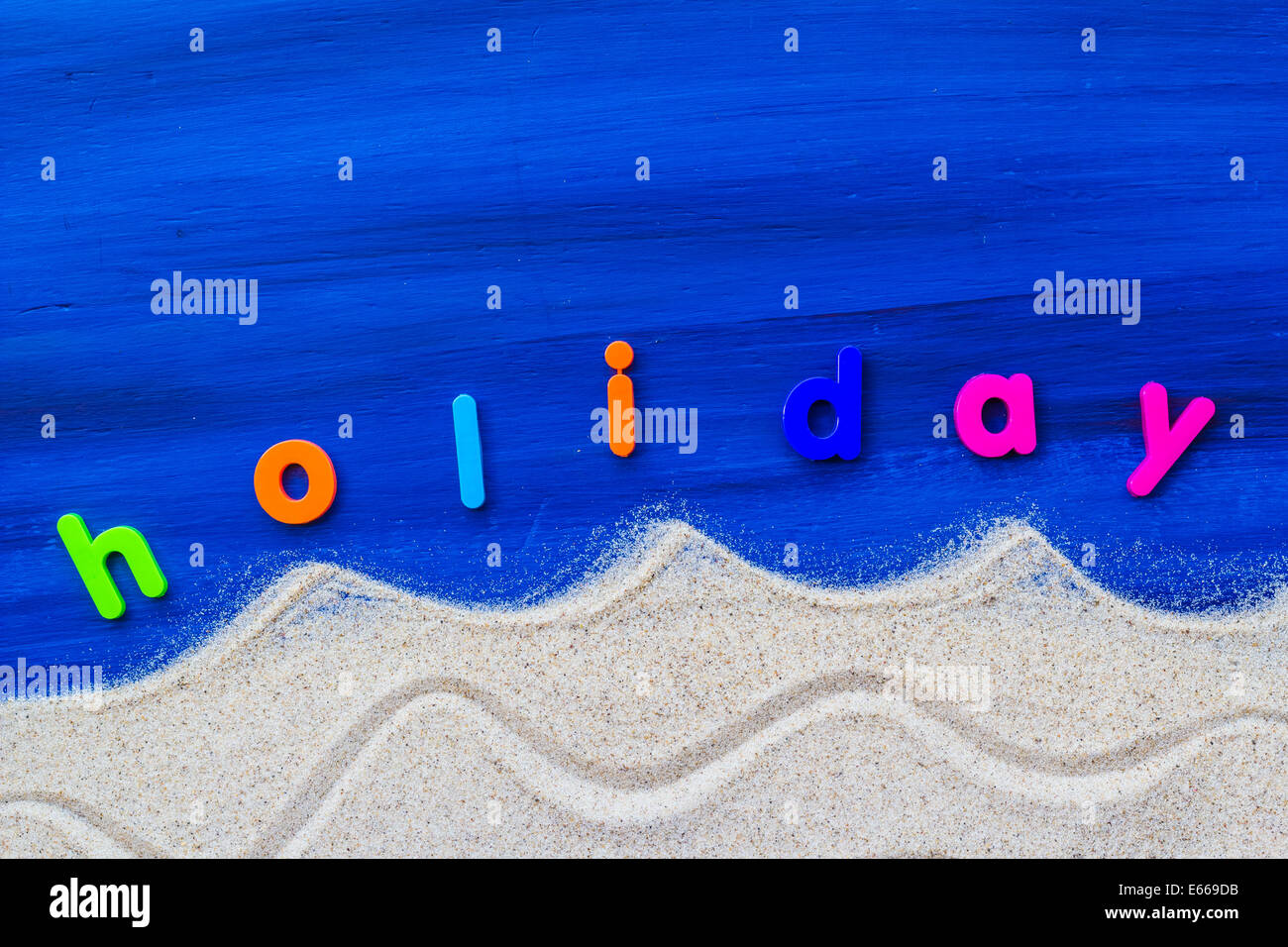 The word holiday laid sand and blue board Stock Photo
