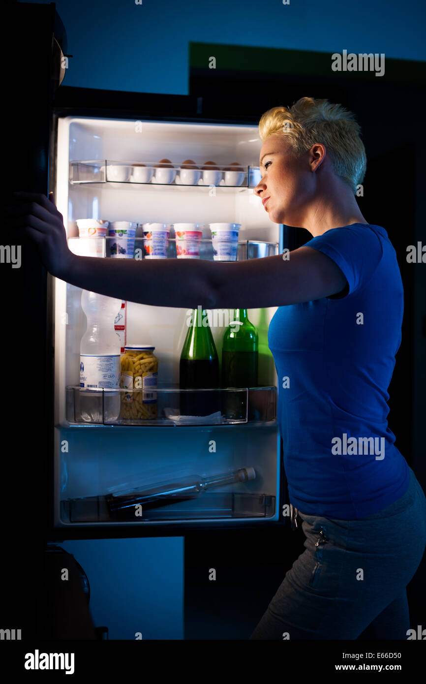Hungry woman searching for food in refregirator late at night Stock Photo