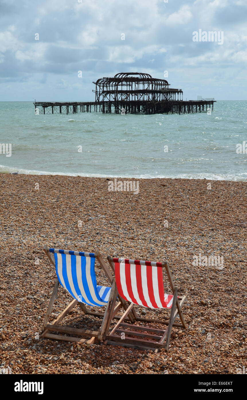 Deck chair's on Brighton beach with the ruined West Pier in view. Stock Photo